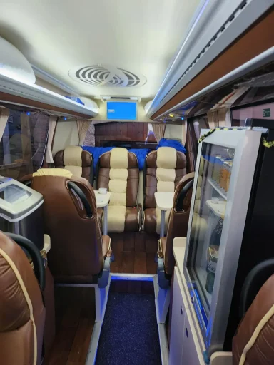 Interior view of a coach with brown and cream seating and a beverage cooler.